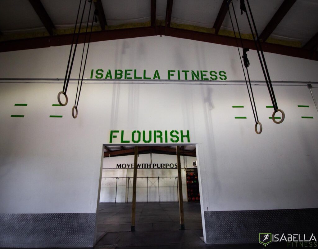 The Isabella Fitness wall mural above the entrance: ISABELLA FITNESS, FLOURISH, and MOVE WITH PURPOSE, flanked by gymnastics rings